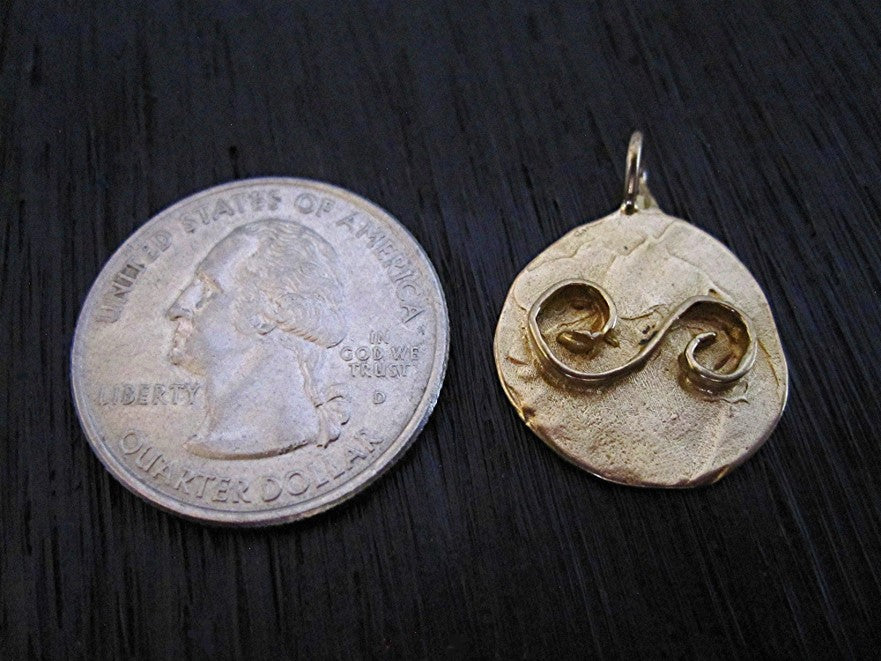 VDI Jewelry Findings Artisan Balance Symbol Charm and Pendant next to a quarter