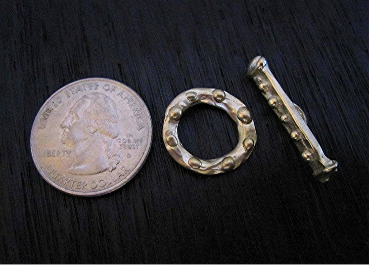 VDI Jewelry Findings Gold Bronze Dotted Toggle Clasp Next to a Quarter