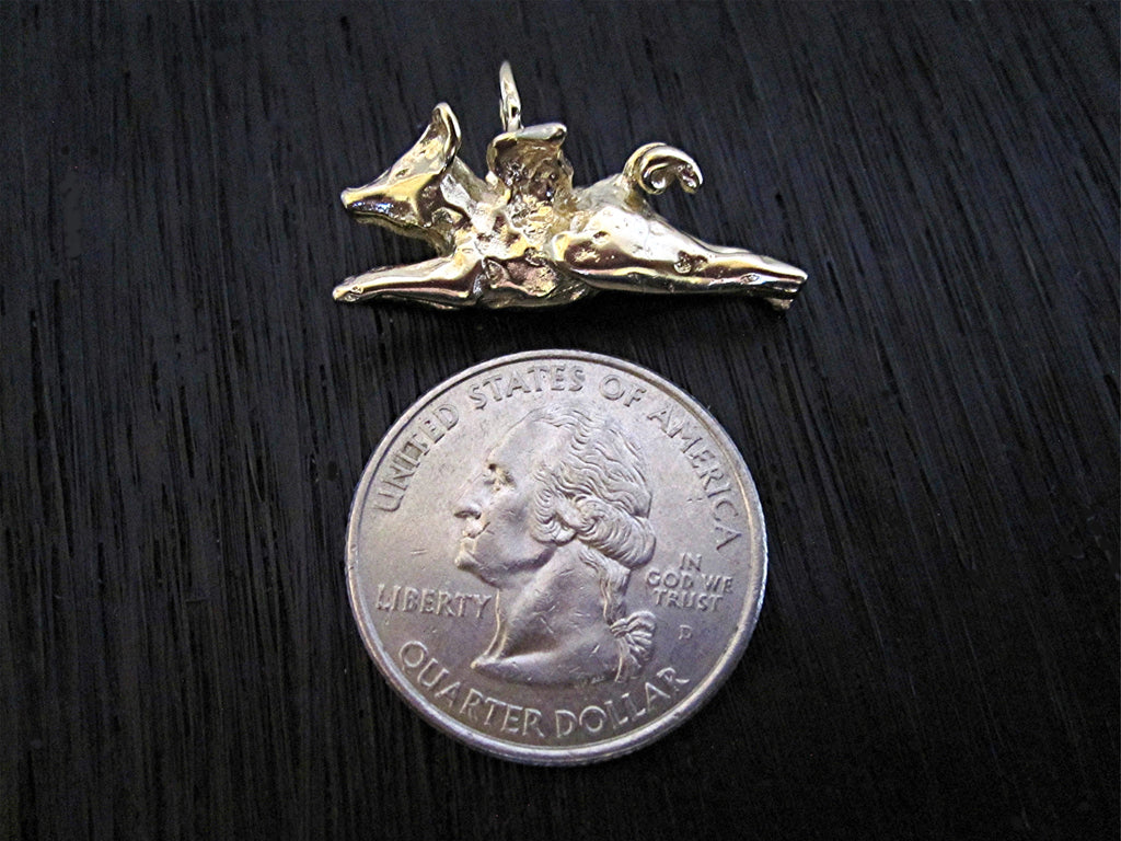 VDI Jewelry Findings Gold Bronze Flying Pig Charm and Pendant next to a quarter