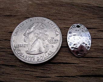 Sterling Silver Oval Hammered Charm Next to a Quarter