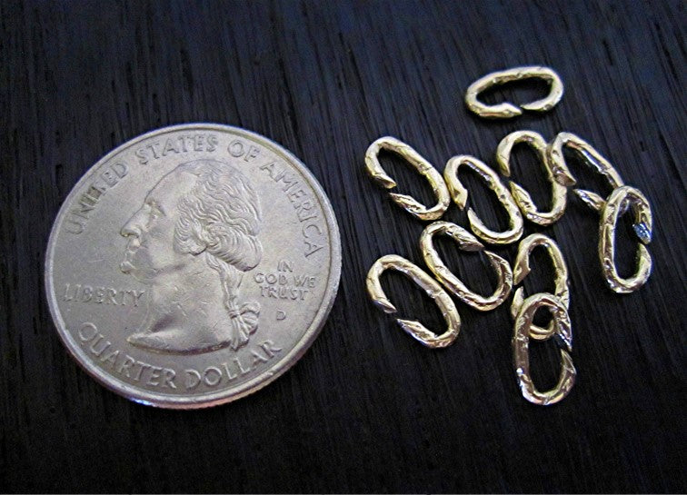 VDI Jewelry Findings Small Oval Gold Bronze Textured No Solder Jump Rings Next to a Quarter